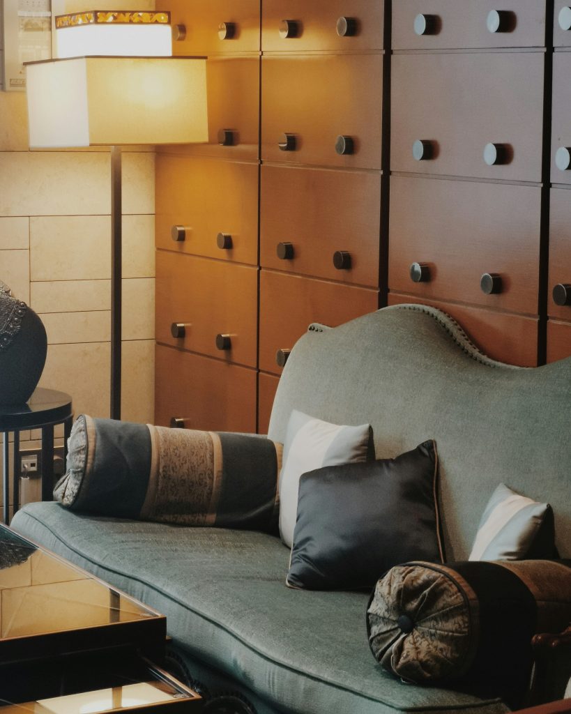 Luxury Art Deco lounge interior with green velvet sofa, lacquered wood cabinetry wall with brass fittings, and a warm amber table lamp — showing how ocean liner interior design influenced modern luxury home decor.