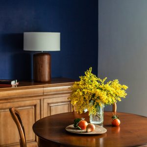 Polished wood and vivid blooms bring warmth to a jewel-toned dining nook. Image source: Unsplash